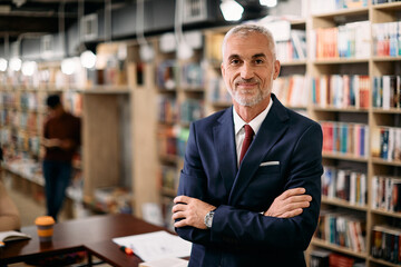 Portrait of confident mature teacher at university library looking at camera.