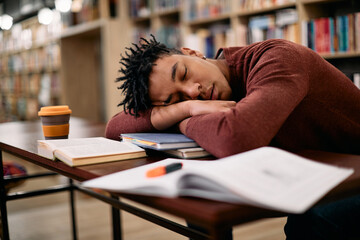 Tired black student fell asleep after learning in a library.