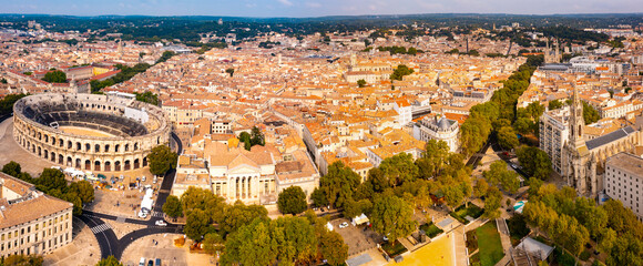 Drone view of ancient Roman amphitheatre Arena of Nimes on background of reddish tiled roofs of...