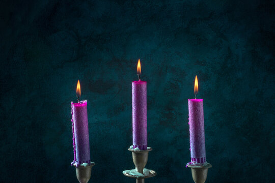 Purple candles, burning, on a dark blue background