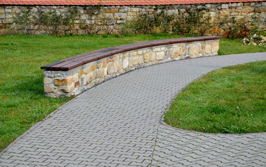 bent sandstone walls made of stone blocks serve as design elements, retaining walls, or seating areas, seats for park visitors. benches made of horizontal wood plank boards