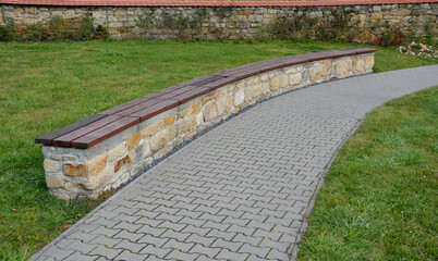 Obraz premium bent sandstone walls made of stone blocks serve as design elements, retaining walls, or seating areas, seats for park visitors. benches made of horizontal wood plank boards