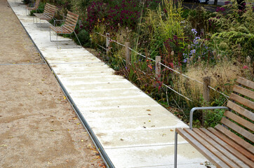 wood benches on their paneling under the benches is a rectangle of concrete anti-scraping beige paths by the shoes of visitors flowering romantic flower beds and lawns