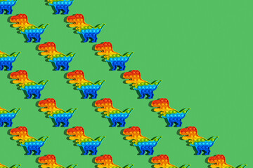 Obraz premium Seamless pattern with Sensory Fidget Toy in the form of dinosaur on green background. Pop It. Anti stress toy.