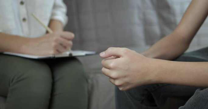 Psychological situation at home. A woman with a notebook try to listen the psychological problems of teen in the room.