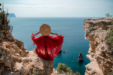 A girl with loose hair in a long red dress descends the stairs between the yellow rocks overlooking...