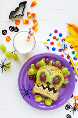 Fun Food for kids - cute Halloween monster sandwich with chocolate spread, fresh grapes and kiwi fruit