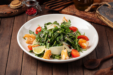 Fresh arugula salad with shrimp on the wooden background
