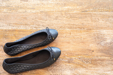 Black ballerina flats on wooden floor. Free space for text.