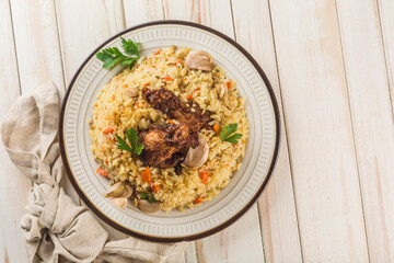 Chicken pilaf in a light plate with baked garlic