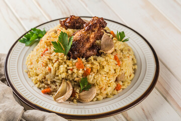 Chicken pilaf in a light plate with baked garlic and fresh herbs