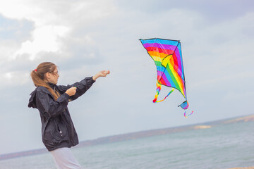 a girl launches a colorful bright kite into the sky