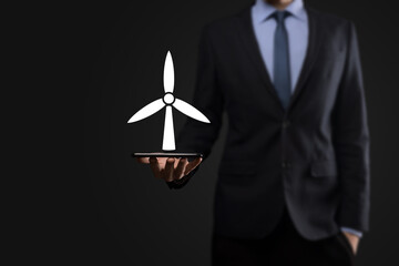 Businessman holding an icon of a windmill that produces environmental energy. Dark background