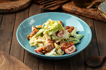 Portion of fresh mixed salad with fried chicken on wooden background