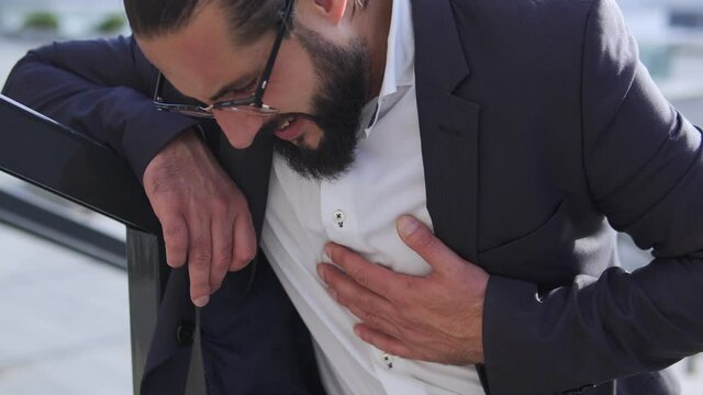 Bearded man hardly breathing feeling heartache, stroke, heart attack, call 911