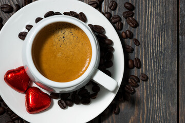 cup of espresso and chocolate sweets in the form of a heart, top view closeup