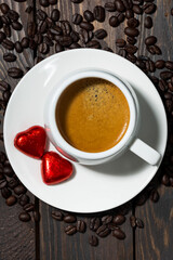 cup of espresso and chocolate sweets in the form of a heart, vertical top view