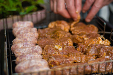 Man puting meat on the grill grate. Rest in the country outside. Barbeque Grill Street Food. Summer barbecue cooking, funny picnic.