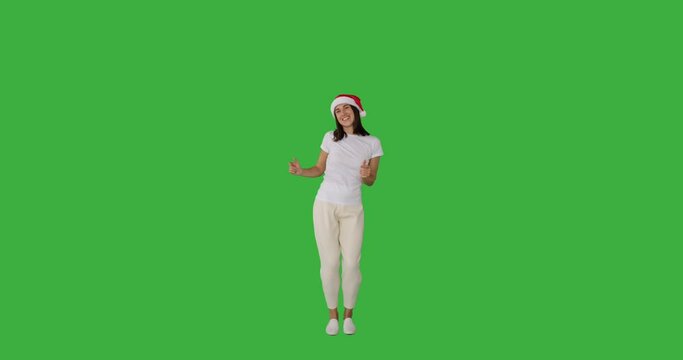 Joyful woman in santa hat dancing over green background