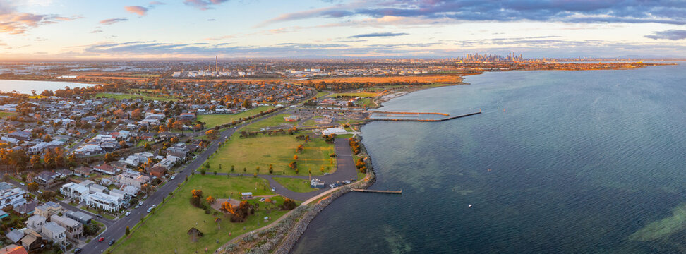 Panoramic aerial view of coastal reserve and parkland next to a calm bay at sunset