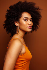 pretty young african american woman with curly hair posing cheerful gesturing on brown background, lifestyle people concept