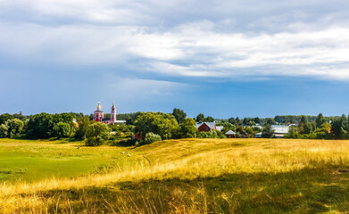 Obraz premium Summer landscape with buildings, churches, trees, shrubs, grass, sky with clouds of the city of Suzdal in Russia