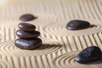 Fototapeta na wymiar Stacked black stones on Zen garden with sand. Spirituality, relaxation and harmony concept.