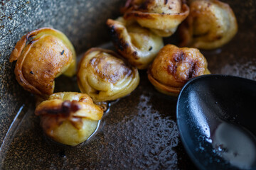 Fried dumplings in oil in a frying pan.
