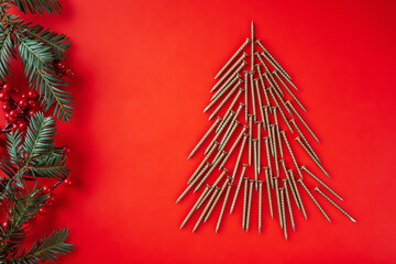 Long golden self-tapping screws, laid out in shape of Christmas tree with spruce branches and...