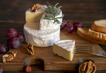 Fototapeta na wymiar Cheese with white mold, nuts and grapes on a wooden cutting board.