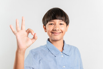 A portrait of a smiling smart boy shows okay gesture confirmation or approval gesture expresses...