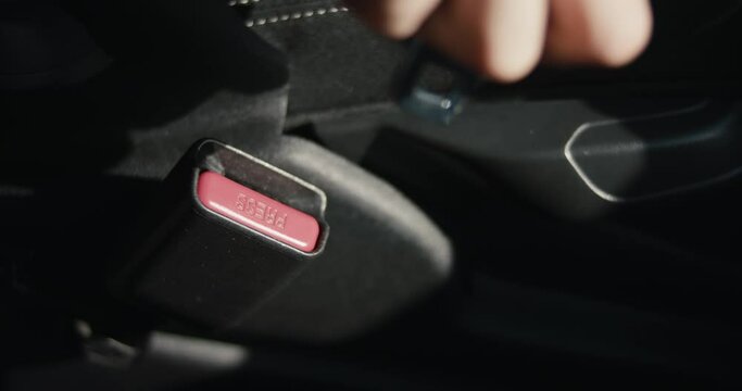 Female hand buckles up safety belt woman inside a car in close up