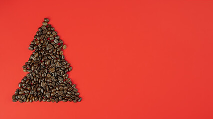 Brown coffee beans laid out in shape of Christmas tree on red background. Banner. Flat lay, copy...