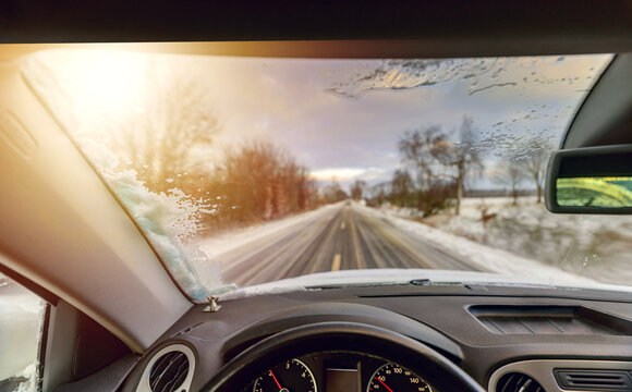 Driving through winter. Vehicle drives  through the winter landscape. Wintercheck. Removed snow from car windshield. Cleaning car window in winter from snow.