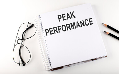 Notepad with text PEAK PERFORMANCE White background. Business concept