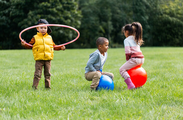 childhood, leisure and people concept - group of happy children playing with hopper balls and hula...