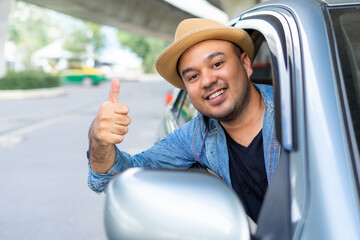 Handsome asian man wear hat the blue jeen shirt is driving and thumbs up sitting on car seat...