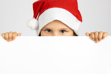 close-up portrait of girl in red Santa hat holding white blank poster isolated on white background with copy space. 