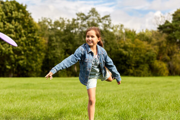 childhood, leisure and people concept - happy girl playing game with flying disc at park