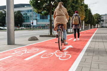 traffic, city transport and people concept - woman cycling behind pedestrian walking along red bike...