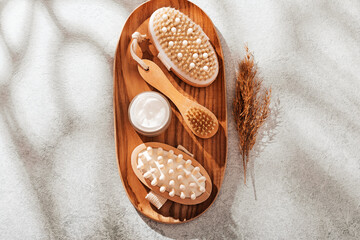 Body brushes and face and body care cosmetics on concrete table with pampas grass