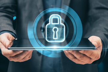 Close up of businessman hand holding tablet with glowing padlock hologram on blurry background. Internet safety and security concept. Double exposure.