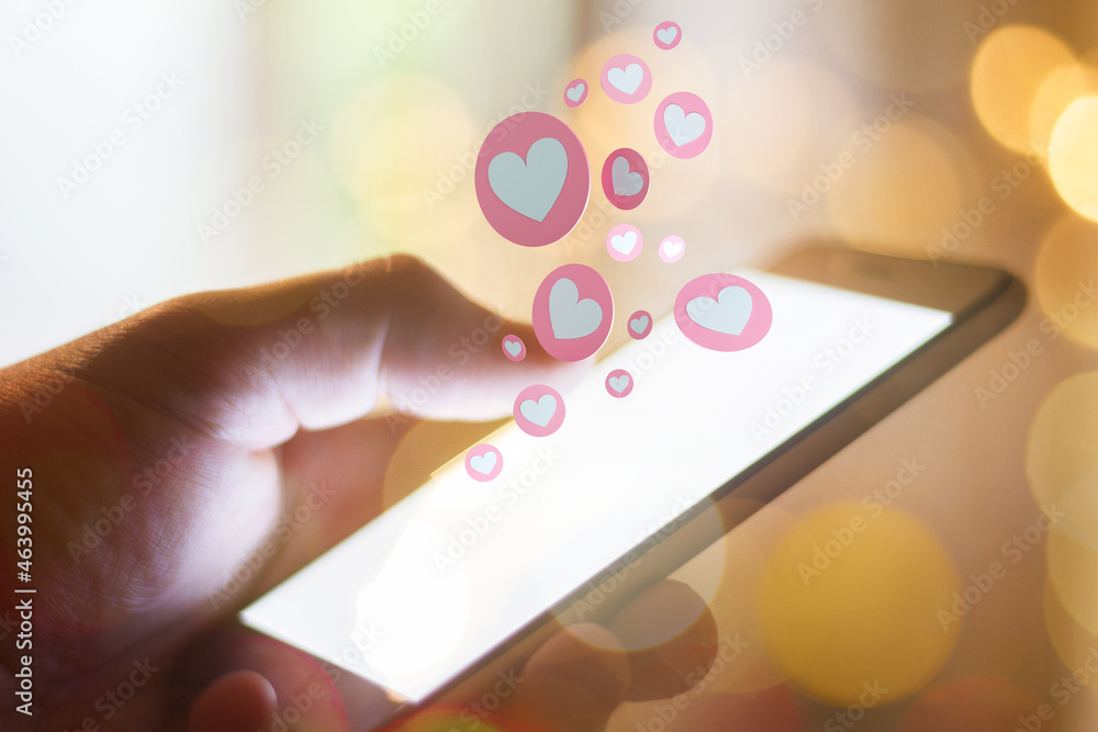 Poster close up of hand using cellular phone with abstract hearts on blurry background bokeh background. li