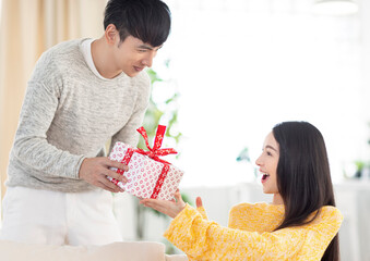 Young couple giving the gift box in living room