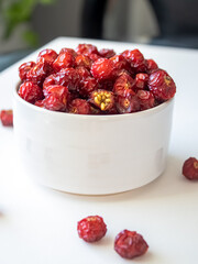 Sun-dried wild rose hip in a white bowl on white background