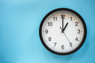 Classic black and white analog clock on blue background at One o'clock with copy space