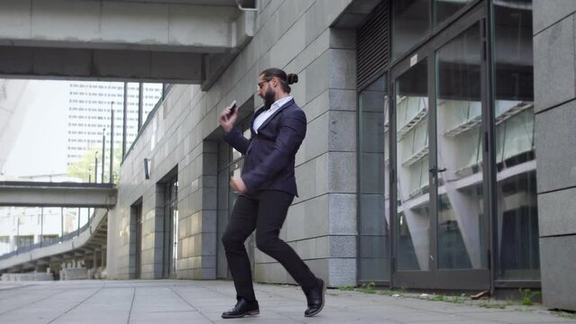 Handsome bearded man dancing outdoor, developing new application for smartphones