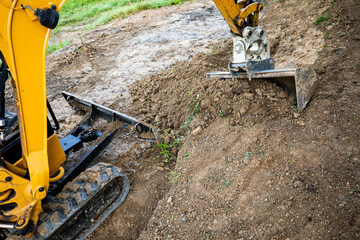 Mini excavator digging preparing ground under home garden - obrazy, fototapety, plakaty