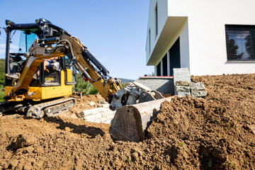 Mini excavator digging preparing ground under home garden - obrazy, fototapety, plakaty