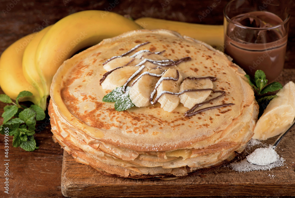 Wall mural isolated desert - stack of pancake with chocolate spread and banana on a wooden table